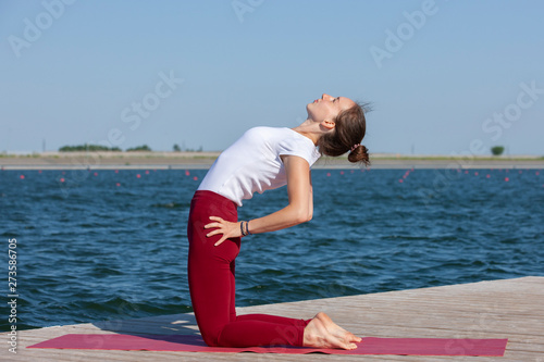 Healthy lifestyle in nature,Woman doing yoga exercise on mat in park near lake.