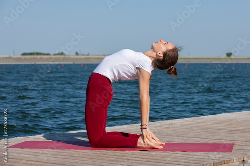 Healthy lifestyle in nature,Woman doing yoga exercise on mat in park near lake.