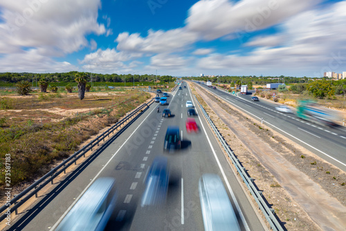A long exposure of a highway near the city of Torrevieja. An exit on the right and a ramp on the left can be seen. Many vehicles are on the way.