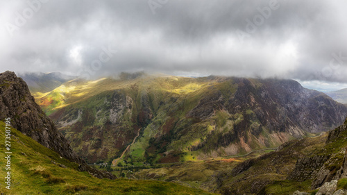 A wild, beautiful and exciting mountain landscape at Snowdonia in North Wales in United Kingdom. Green mountains, dark clouds and a sunshine area.