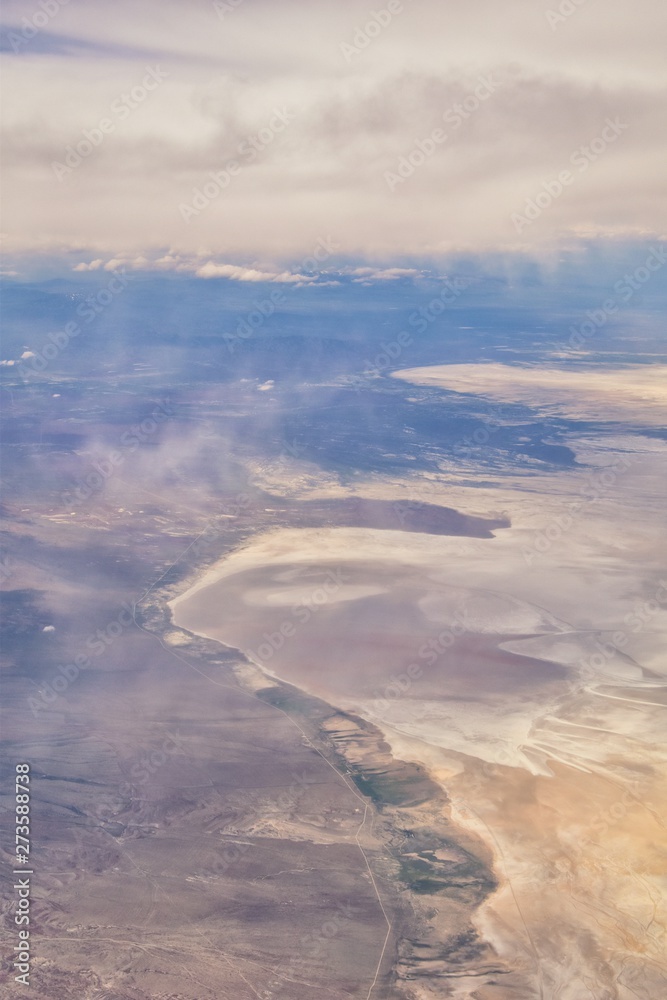 Obraz premium Aerial view from airplane of the Great Salt Lake in Rocky Mountain Range, sweeping cloudscape and landscape during day time in Spring. In Utah, United States.