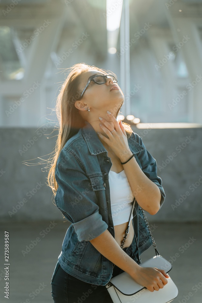 Fototapeta premium Beautiful young girl on the streets of modern town in glasses. Leisure, beauty, fashion concept