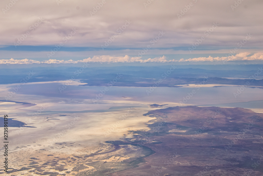 Aerial view from airplane of the Great Salt Lake in Rocky Mountain Range, sweeping cloudscape and landscape during day time in Spring. In Utah, United States.