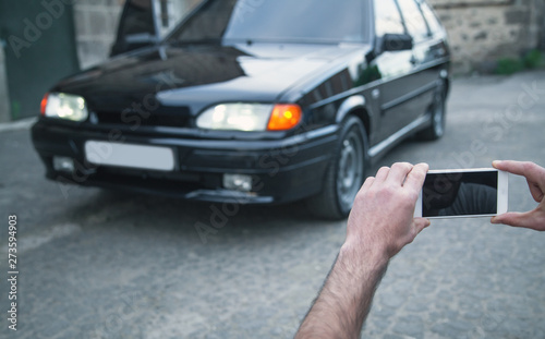 Man taking photo of a car on his phone.