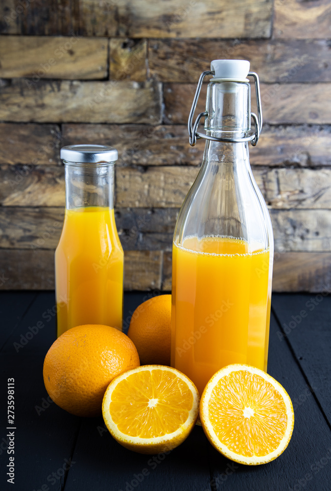still life photo of orange juice, orange smoothie in glass bottles on wooden background. still life photo of orange juice, orange smoothie in glass bottles on wooden background.