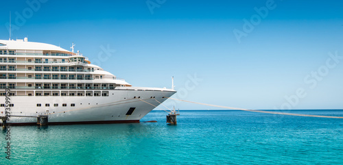 Side view and bow of a docked cruise ship on a summer day with clear blue sky