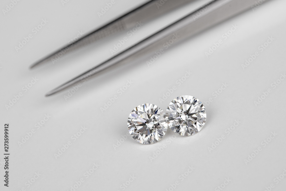 Carat size diamonds compared with tweezers on white isolated Carat size diamonds compared with tweezers on white isolated