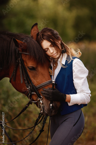 Girl rider horseman hugs brown horse with eyes closed. Concept love for animals.
