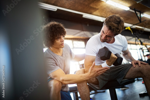 Young fit man doing workout with a personal trainer.