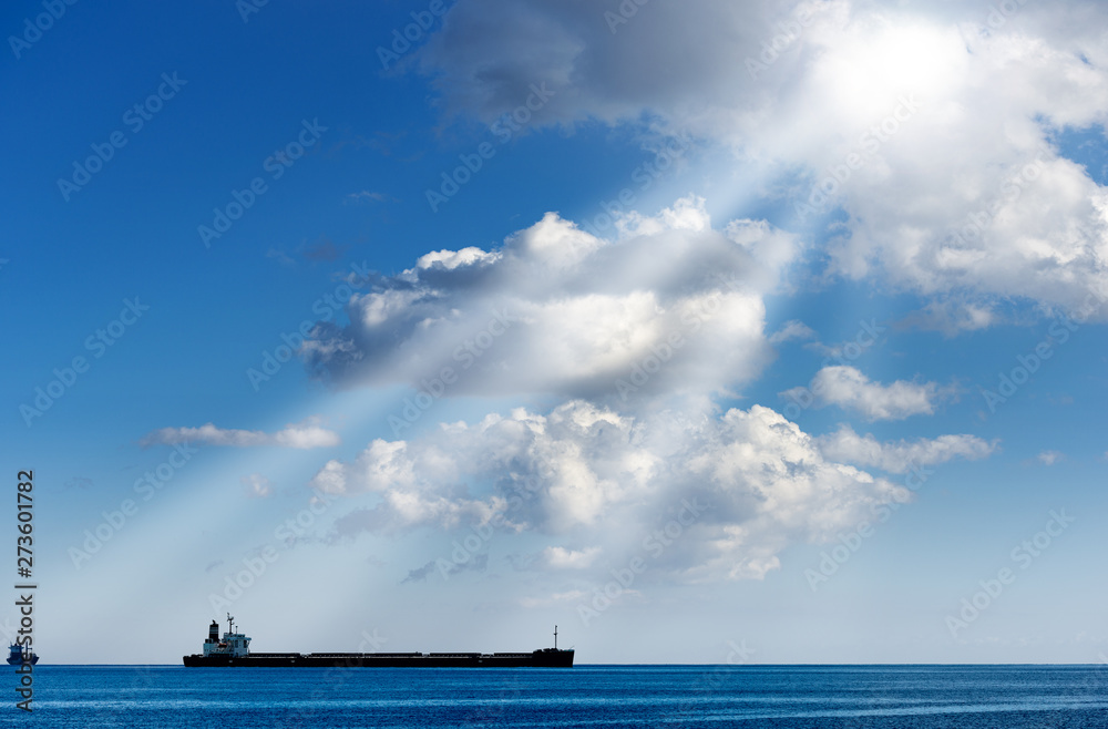 Two empty container ships in the Mediterranean Sea with blue sky, clouds and sun rays