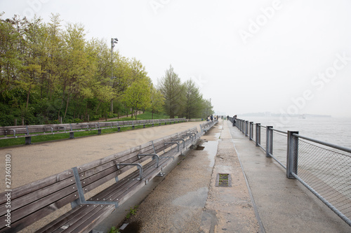 Long wooden bench, wet and empty after the rain, green grass and trees at Hadson river Manhattan New York photo