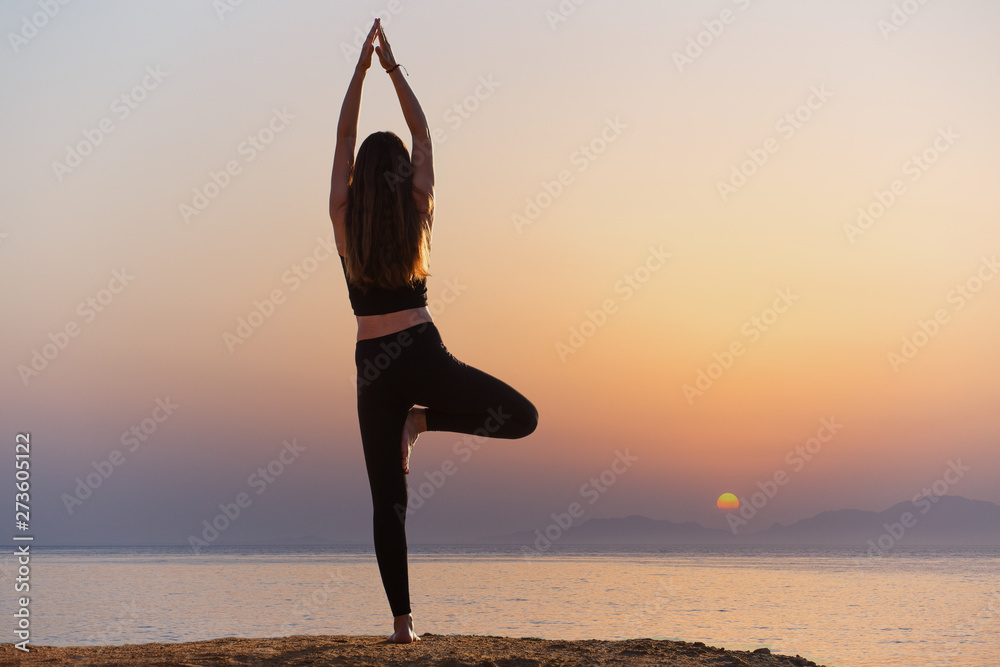 Young woman practicing yoga asana pose in the morning at the sea