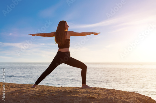 Young woman practicing yoga asana pose in the morning at the sea