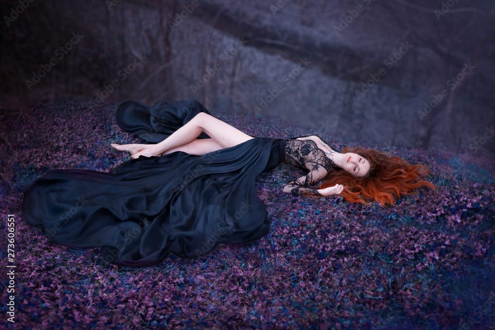 lady sleeping on the ground with long red fiery hair lies in a ...