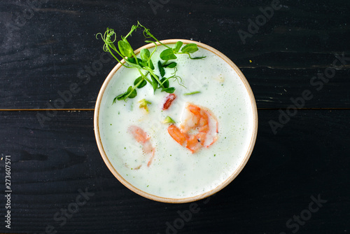 Vegetable cream soup with shrimps and croutons in bowl over wooden background with copy space