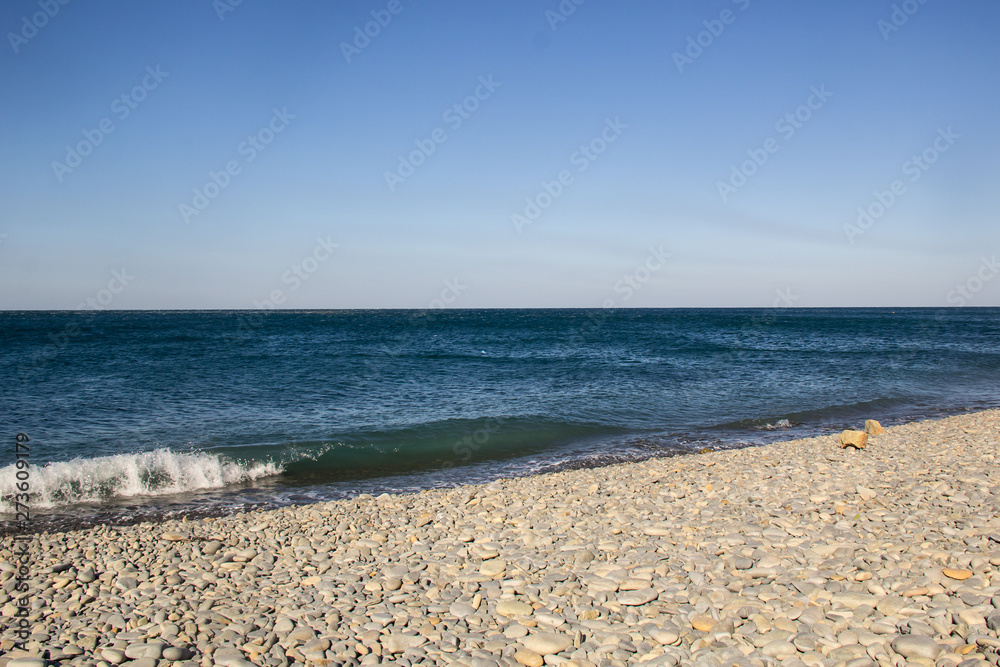 The sea foamy waves on an empty pebble beach