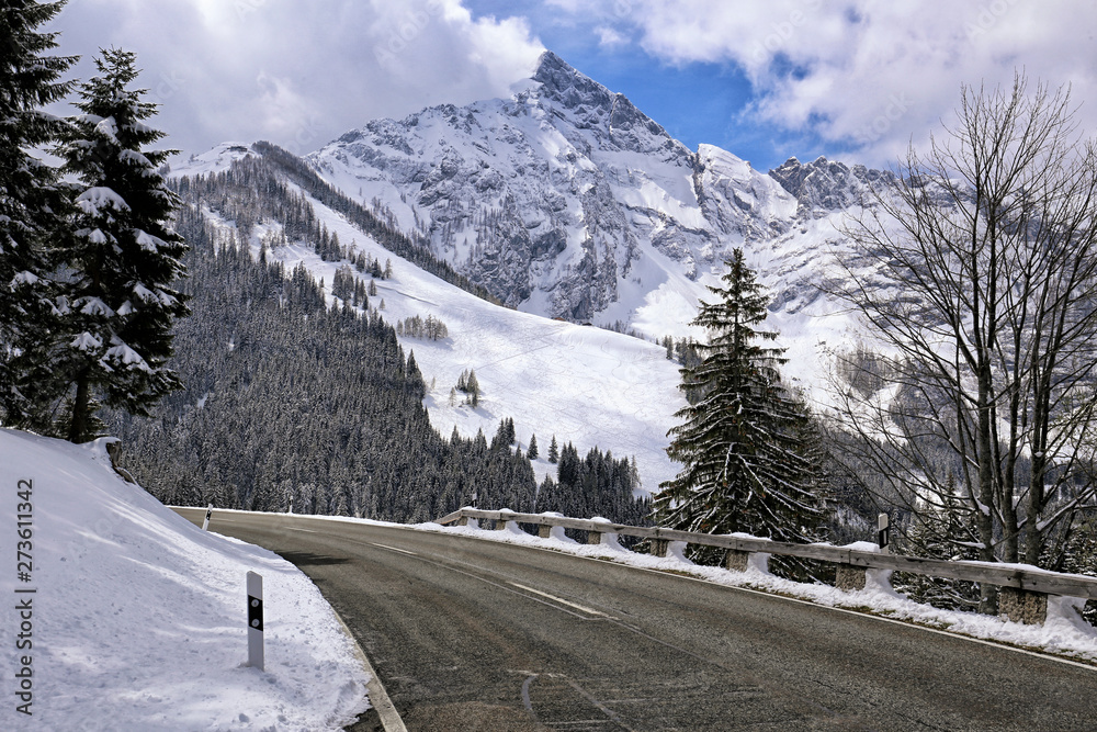 Asphalt road Rossfeldstrasse in the Alps with snow on sides