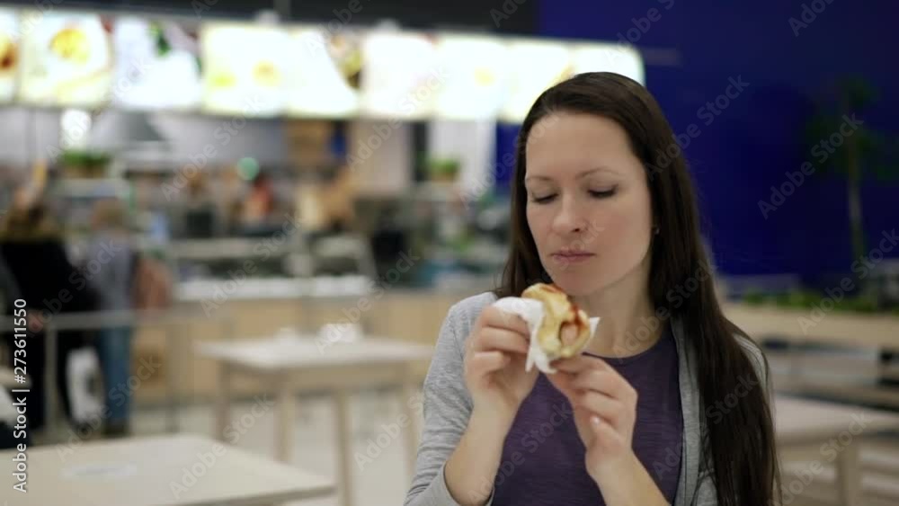 Hungry woman eating at food court in shopping mall. Young pretty woman chewing tasty hot dog at fast food restaurant. Unhealthy food. lady eating cheap street snack, addicted to high calorie junk food Hungry woman eating at food court in shopping mall. Young pretty woman chewing tasty hot dog at fast food restaurant. Unhealthy food. lady eating cheap street snack, addicted to high calorie junk food