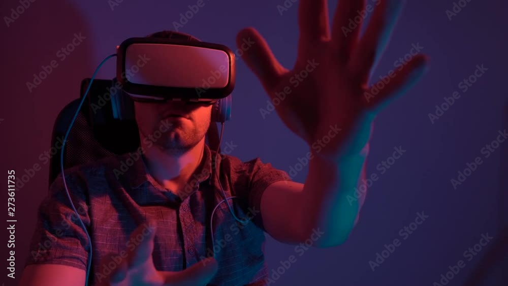 A man wearing virtual reality glasses and headphones sits on a chair. 4k video A man wearing virtual reality glasses and headphones sits on a chair. 4k video