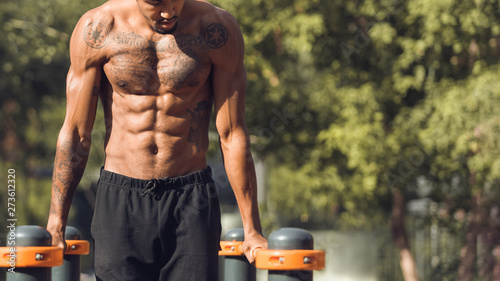 Fotografie Muscular Shirtless Man Doing Push Ups On Parallel Bars