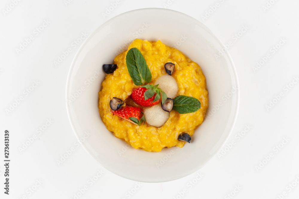 Yellow corn porridge with milk, berries, mint for a healthy nutritious breakfast, isolated in white Yellow corn porridge with milk, berries, mint for a healthy nutritious breakfast, isolated in white