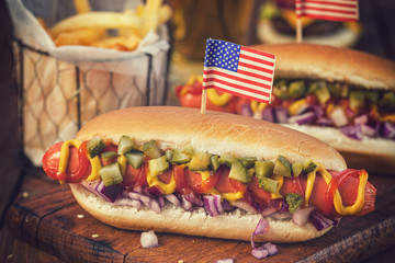 American hot dog with pickles,onions, ketchup, mustard and french fries at a picnic for fourth of July