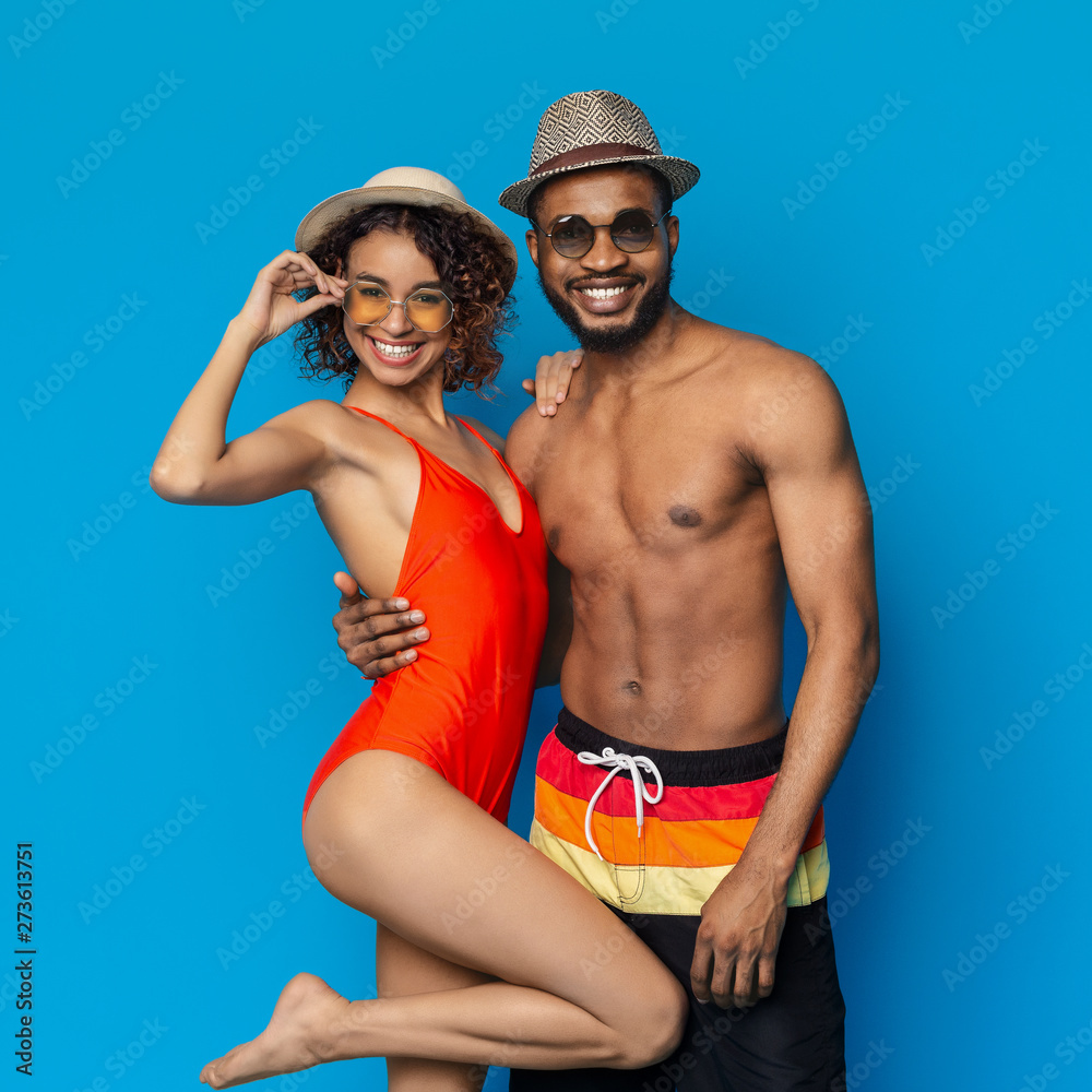 Happy loving african couple in swimwear embracing on blue Happy loving african couple in swimwear embracing on blue