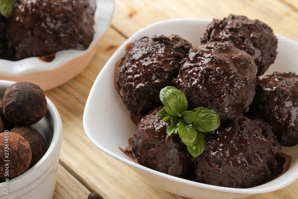 Chocolate ice cream with liquid chocolate and cinnamon sticks on a light concrete background. Chocolate ice cream with liquid chocolate and cinnamon sticks on a light concrete background.