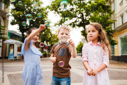 Little friends are walking around the city. Children catch and burst soap bubbles.