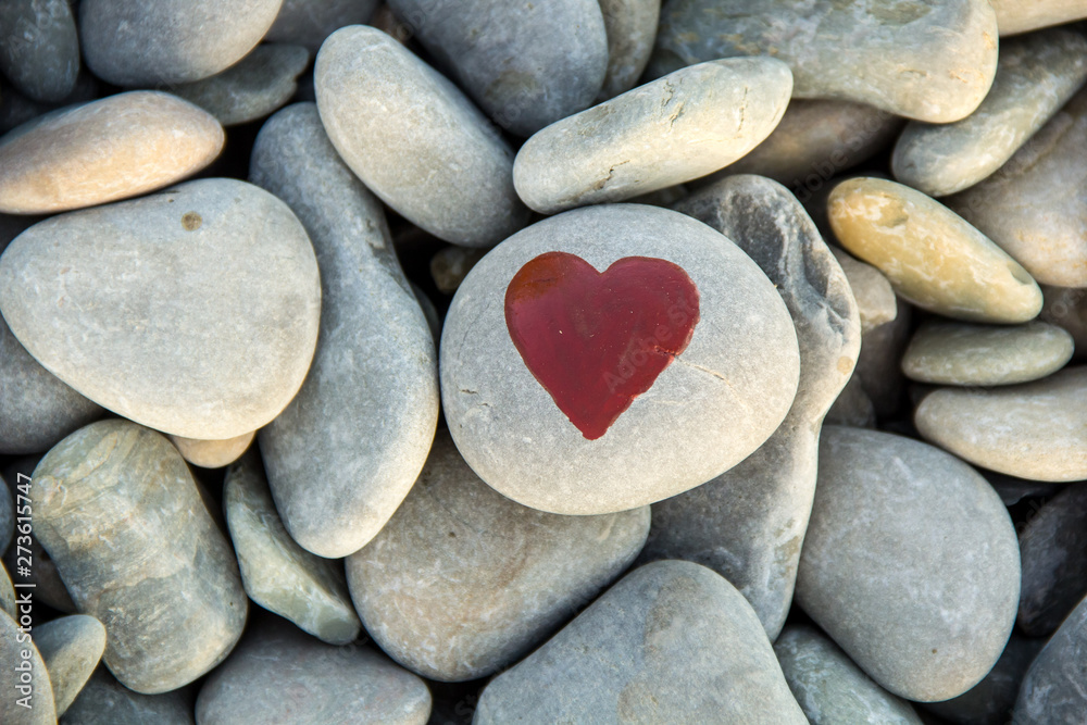 stone heart painted with a red paint marker on the pebble as a gift for Saint Valentine day on the pebble background. stone heart painted with a red paint marker on the pebble as a gift for Saint Valentine day on the pebble background.