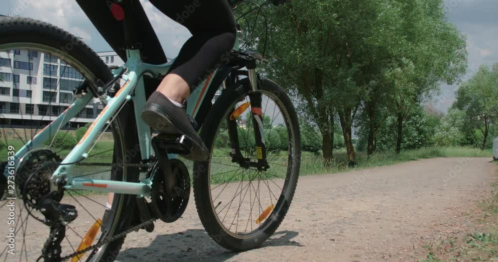 Young girl ride a bike in a city nature park, near the river and modern buildings, calm mood, 4k slow motion. Young girl ride a bike in a city nature park, near the river and modern buildings, calm mood, 4k slow motion.