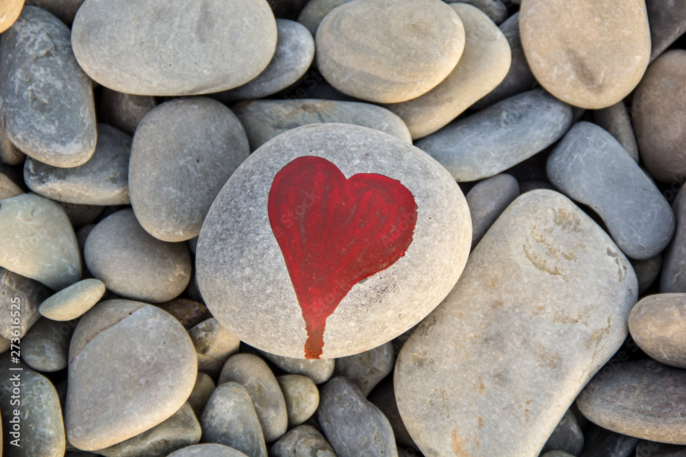 stone heart painted with a red paint marker on the pebble as a gift for Saint Valentine day on the pebble background. stone heart painted with a red paint marker on the pebble as a gift for Saint Valentine day on the pebble background.
