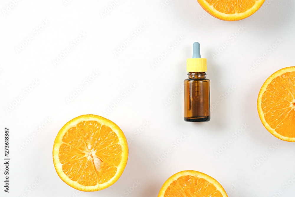 Bottle citrus essential oil and fresh juicy orange fruit on white background. High dose vitamin c synthetic for skin. Flat lay, top view, copy space Bottle citrus essential oil and fresh juicy orange fruit on white background. High dose vitamin c synthetic for skin. Flat lay, top view, copy space