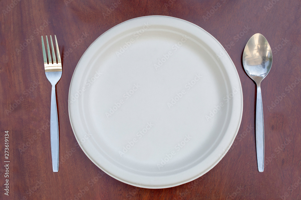Paper plates can be resized on a wooden floor with a spoon and stainless steel fork placed. Paper plates can be resized on a wooden floor with a spoon and stainless steel fork placed.