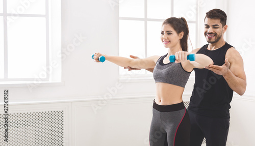 Personal trainer coaching young girl to exercise with dumbbells © Prostock-studio