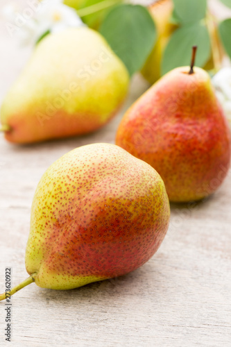 Fresh pears with leaves in a on wooden background.