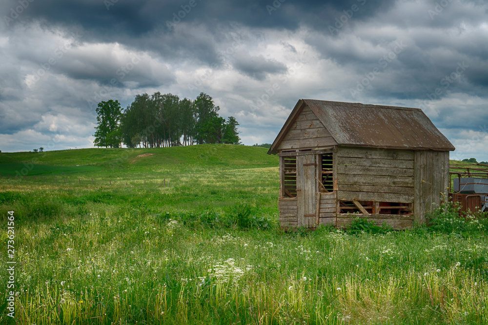 Old dilapidated wooden hut in a farm field
