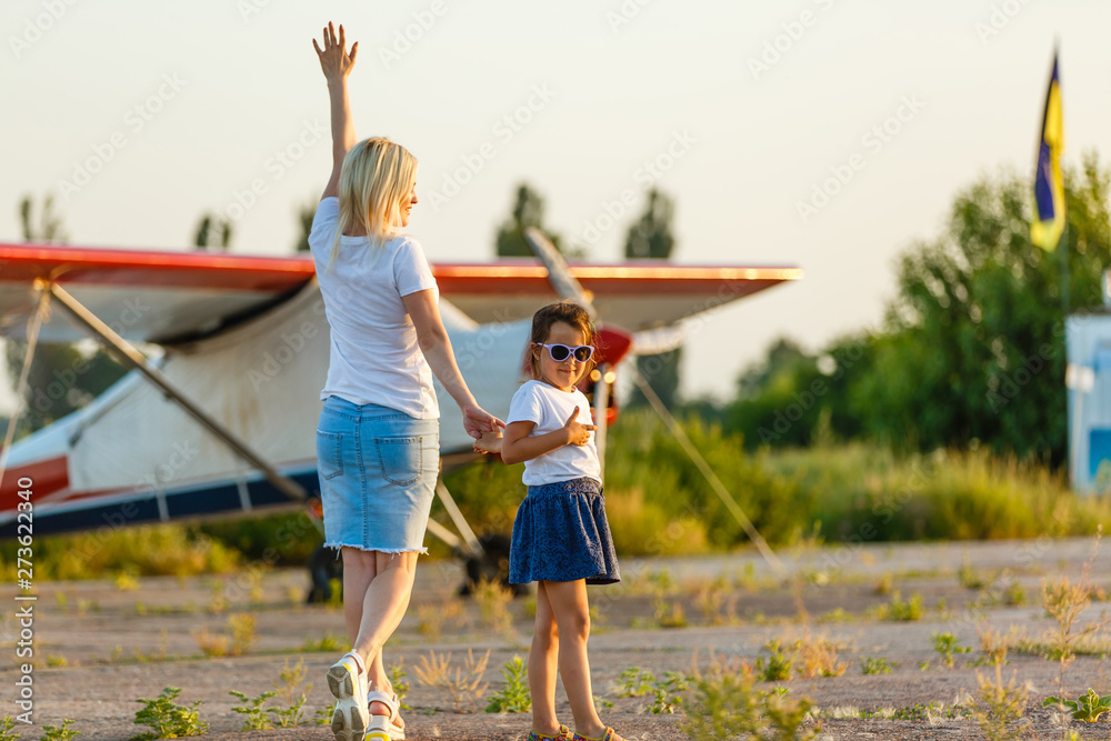 Obraz premium Back view of cheerful mother and daughter smiling plane while spending time in green field together