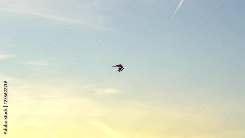 Beautiful hang glider flying in blue sky on sunset, outdoors Beautiful hang glider flying in blue sky on sunset, outdoors