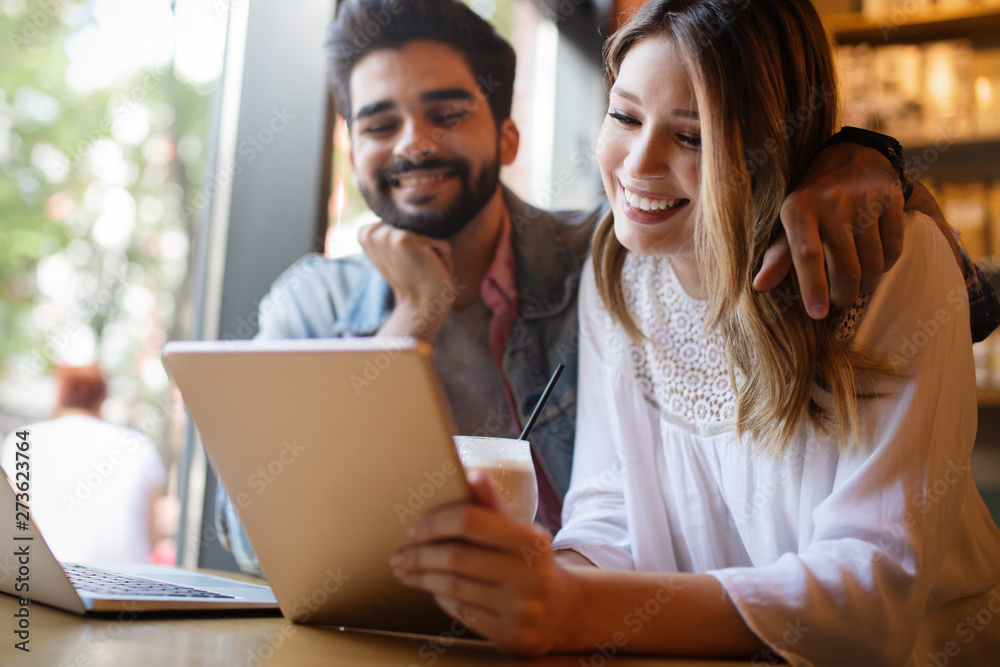 Couple have fun while looking on laptop at cafe