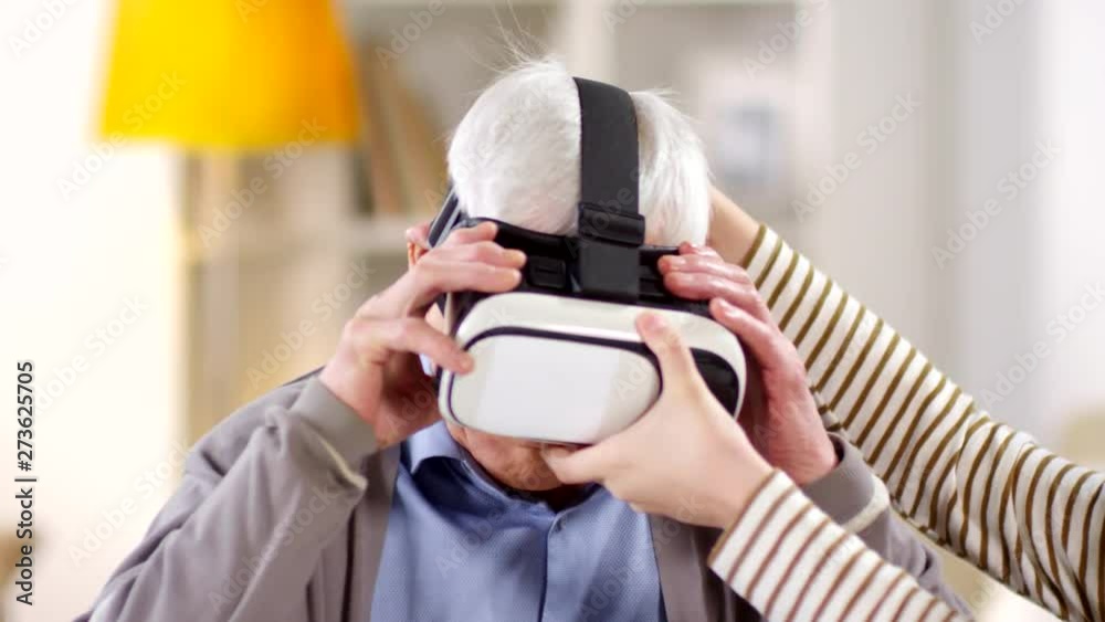 Medium shot of male hands helping senior man putting on VR glasses Medium shot of male hands helping senior man putting on VR glasses