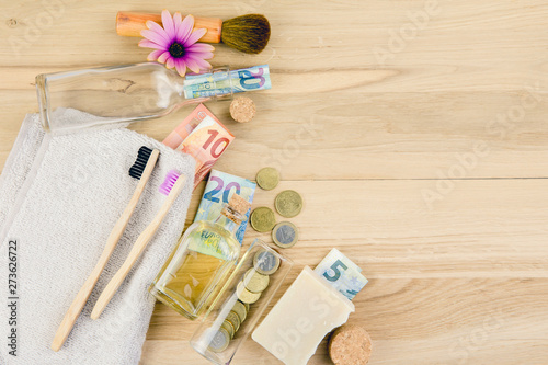 Set of different zero waste beauty products on wooden background with euro money bank notes around them, zero waste sustainable lifestyle true cost concept. 