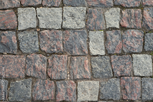 Stone pavement texture, granite cobblestoned pavement background, cobbled stone road regular shapes, abstract background of old cobblestone pavement close-up
