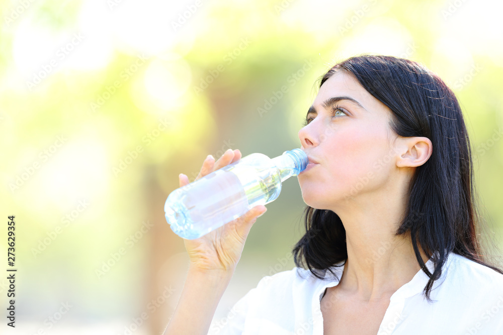 Adult woman drinking water from a plastic bottle Adult woman drinking water from a plastic bottle