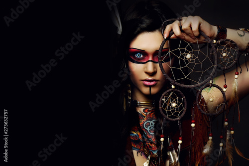 Beautiful woman in native american costume posing in a studio with dream catcher photo