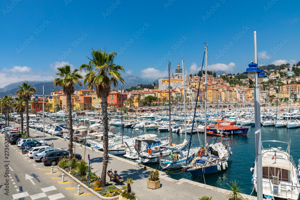 View of palm tree and harbor with boats in Menton on French Riviera. Provence-Alpes-Cote d'Azur, France.