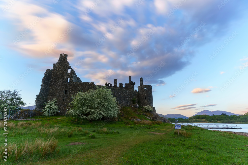 Kilchurn Castle , in the care of Historic Environment Scotland , is a ruined structure on a rocky peninsula at Loch Awe in twilight , Argyll and Bute, Scotland