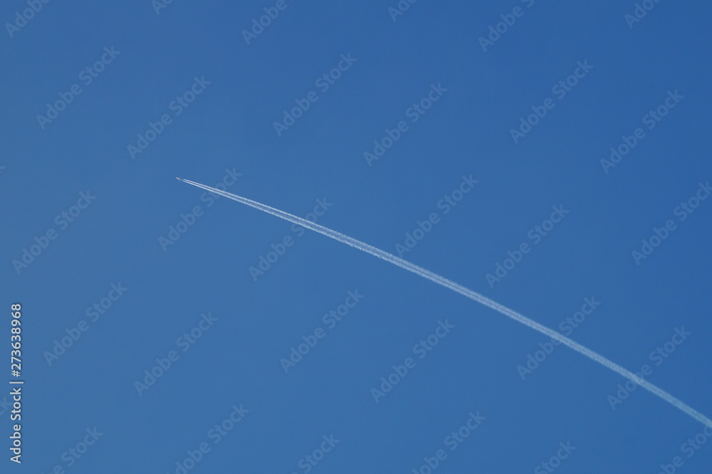 A jet plane is flying in a clear blue sky, leaving behind a white smoke plume. A jet plane is flying in a clear blue sky, leaving behind a white smoke plume.