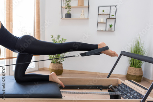 Young woman exercising on pilates reformer bed photo