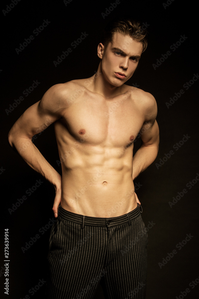 Muscle strong beautiful stripped male model in black jeans on black isolated font background Muscle strong beautiful stripped male model in black jeans on black isolated font background
